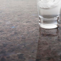 A shiny brown stone surface with a glass on top